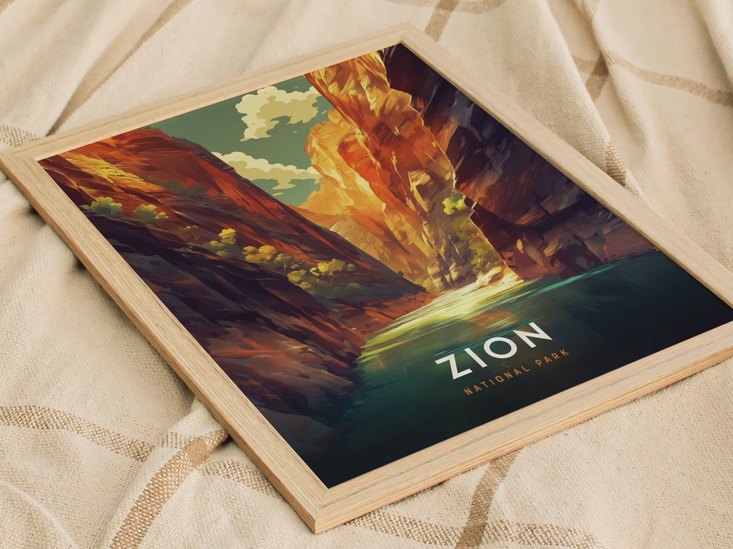 Framed poster of Zion National Parks The Narrows, depicting vibrant red rock cliffs and a serene river under a blue sky, resting on a textured beige fabric.