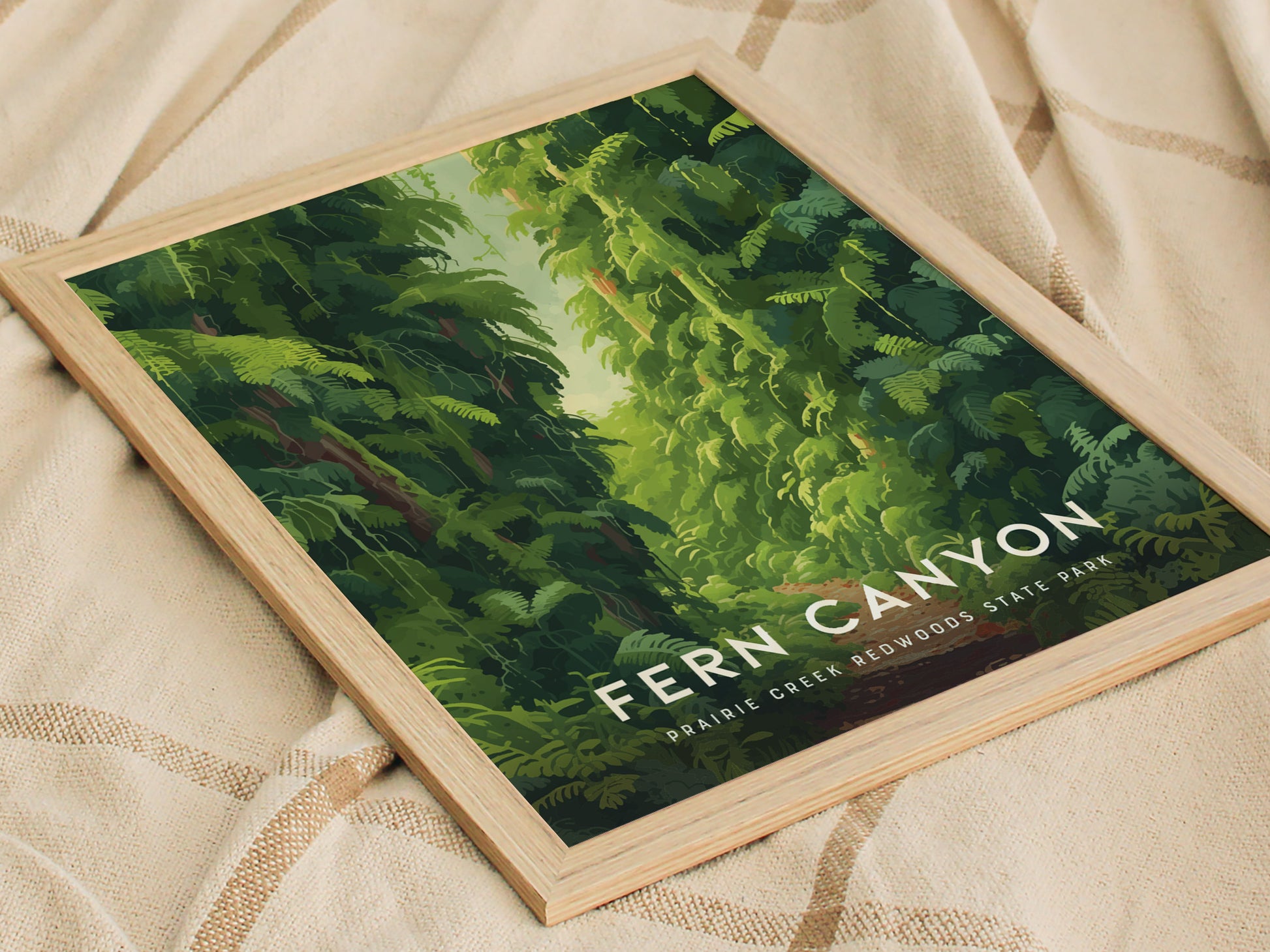 Framed poster featuring lush green ferns and a path through Fern Canyon, Prairie Creek Redwoods State Park, resting on a beige fabric with a checkered pattern.