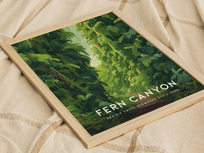 Framed poster featuring lush green ferns and a path through Fern Canyon, Prairie Creek Redwoods State Park, resting on a beige fabric with a checkered pattern.