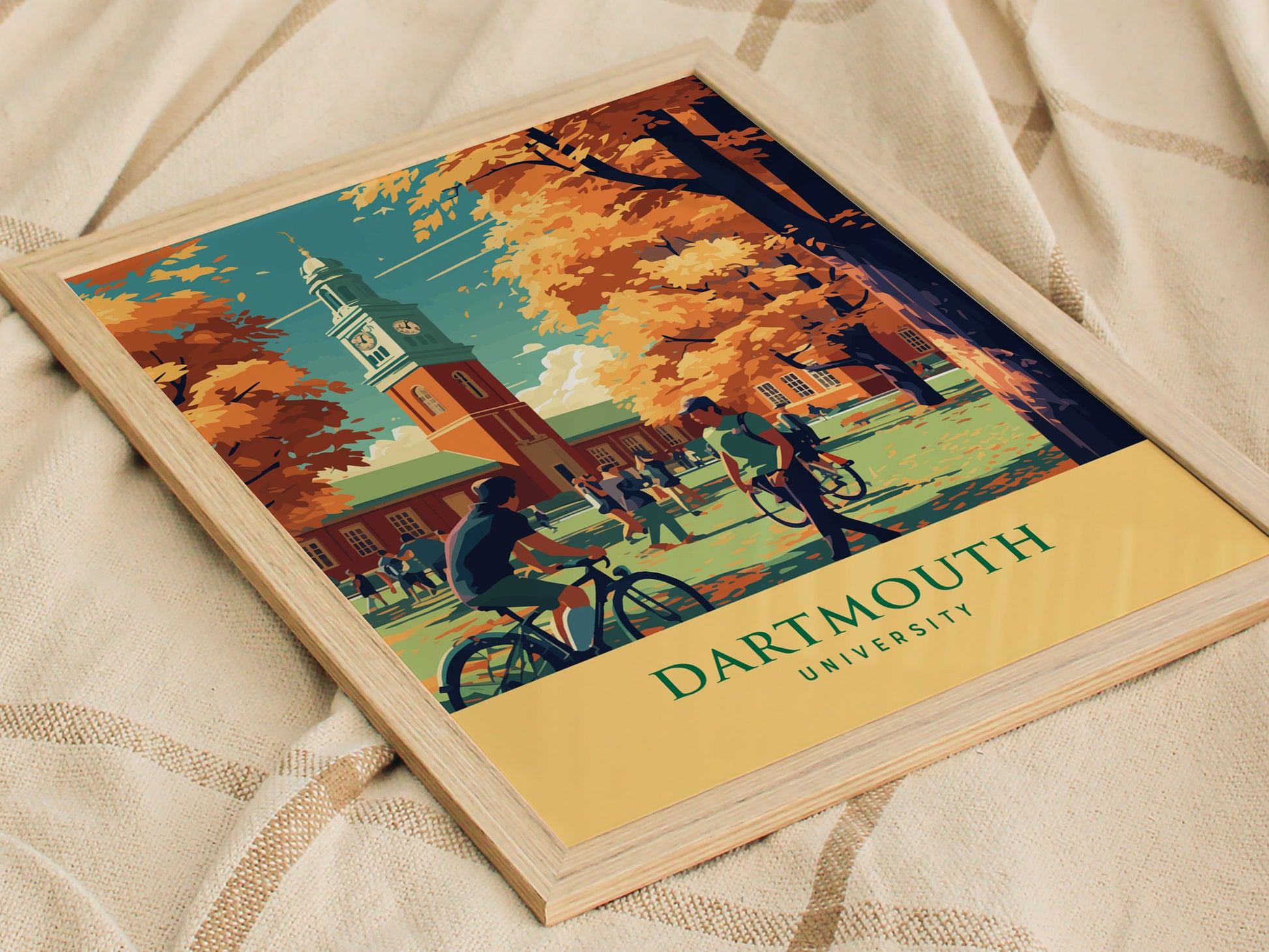 Framed Dartmouth University poster depicting a vibrant campus scene with students walking and cycling under autumn trees, set against a historic clock tower.