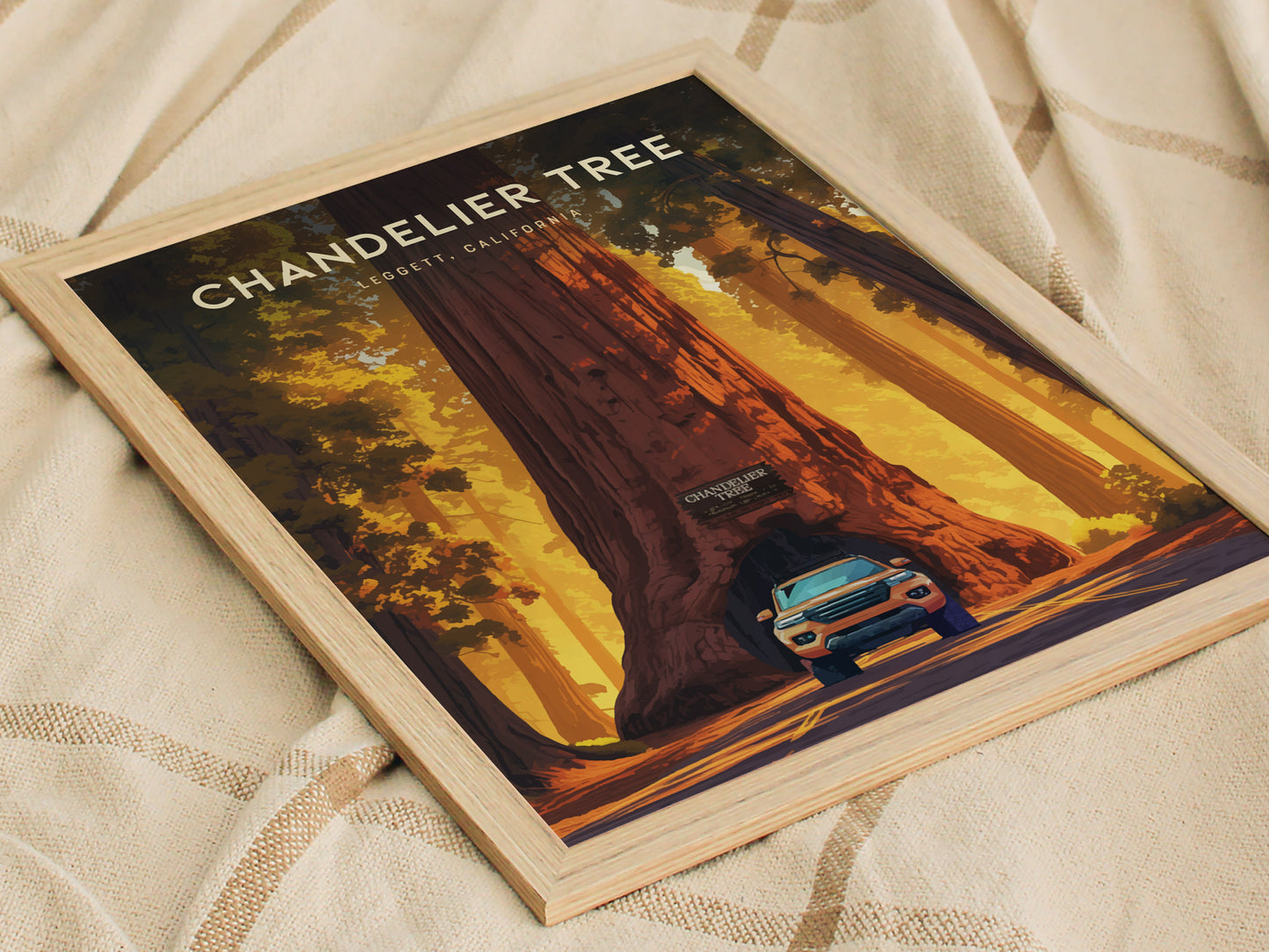 Framed poster of the Chandelier Tree in Leggett, California, featuring a car driving through the tunnel carved into the massive redwood, set against a warm, golden forest background.