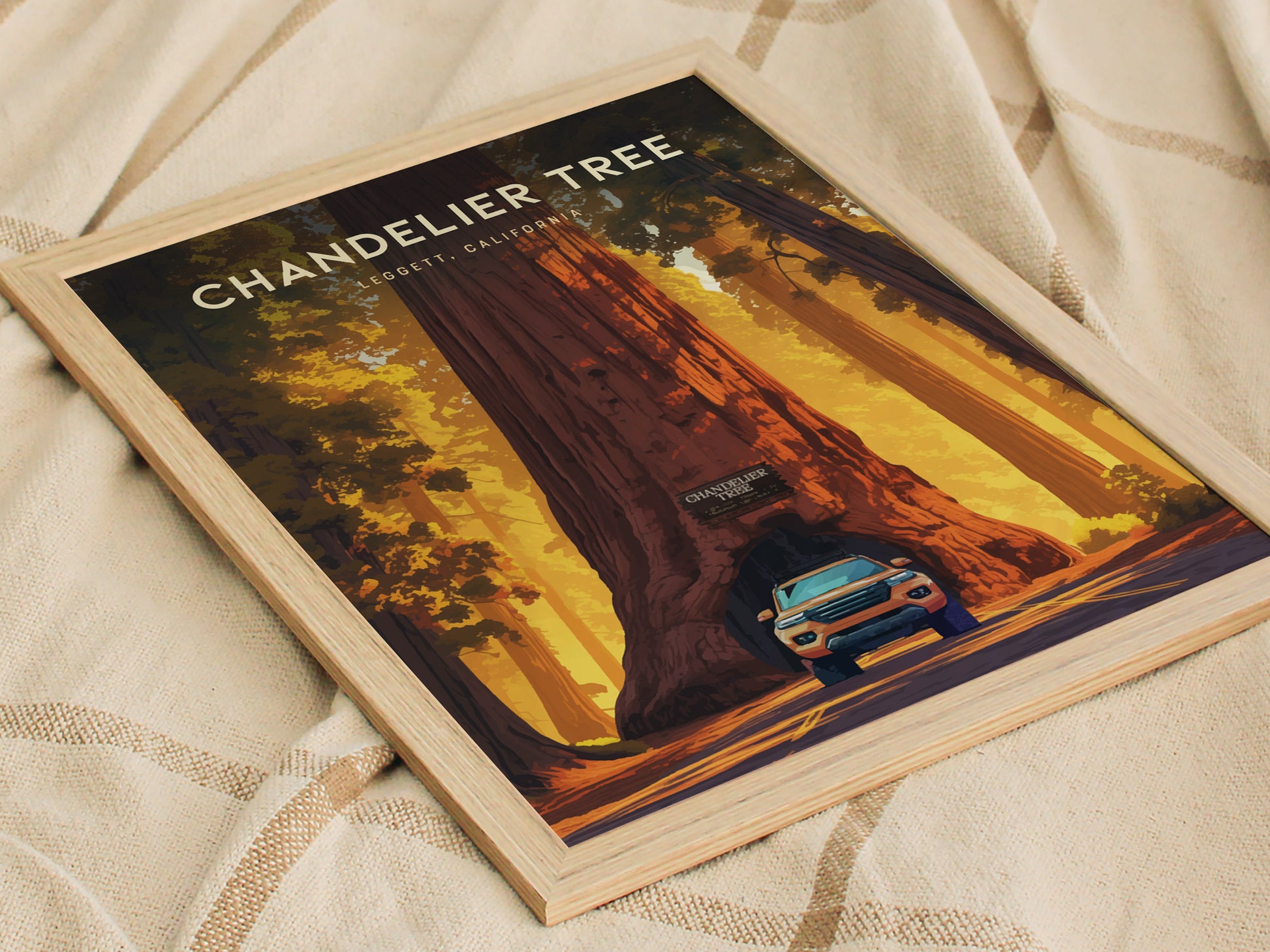 Framed poster of the Chandelier Tree in Leggett, California, featuring a car driving through the tunnel carved into the massive redwood, set against a warm, golden forest background.