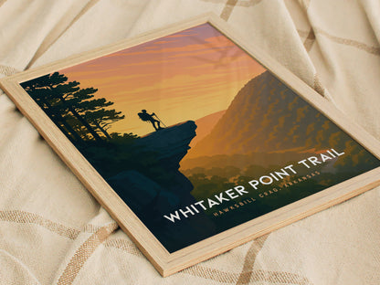 A framed print showcases a scenic view of Whitaker Point Trail in Hawksbill Crag, Arkansas. The artwork features a silhouette of a hiker standing on a cliff, with a vibrant sunset casting warm orange and yellow hues over the landscape.