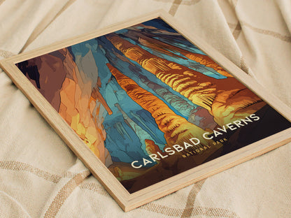 A framed poster of Carlsbad Caverns National Park displays vibrant rock formations in orange, blue, and brown hues, resting on a soft, beige fabric surface.