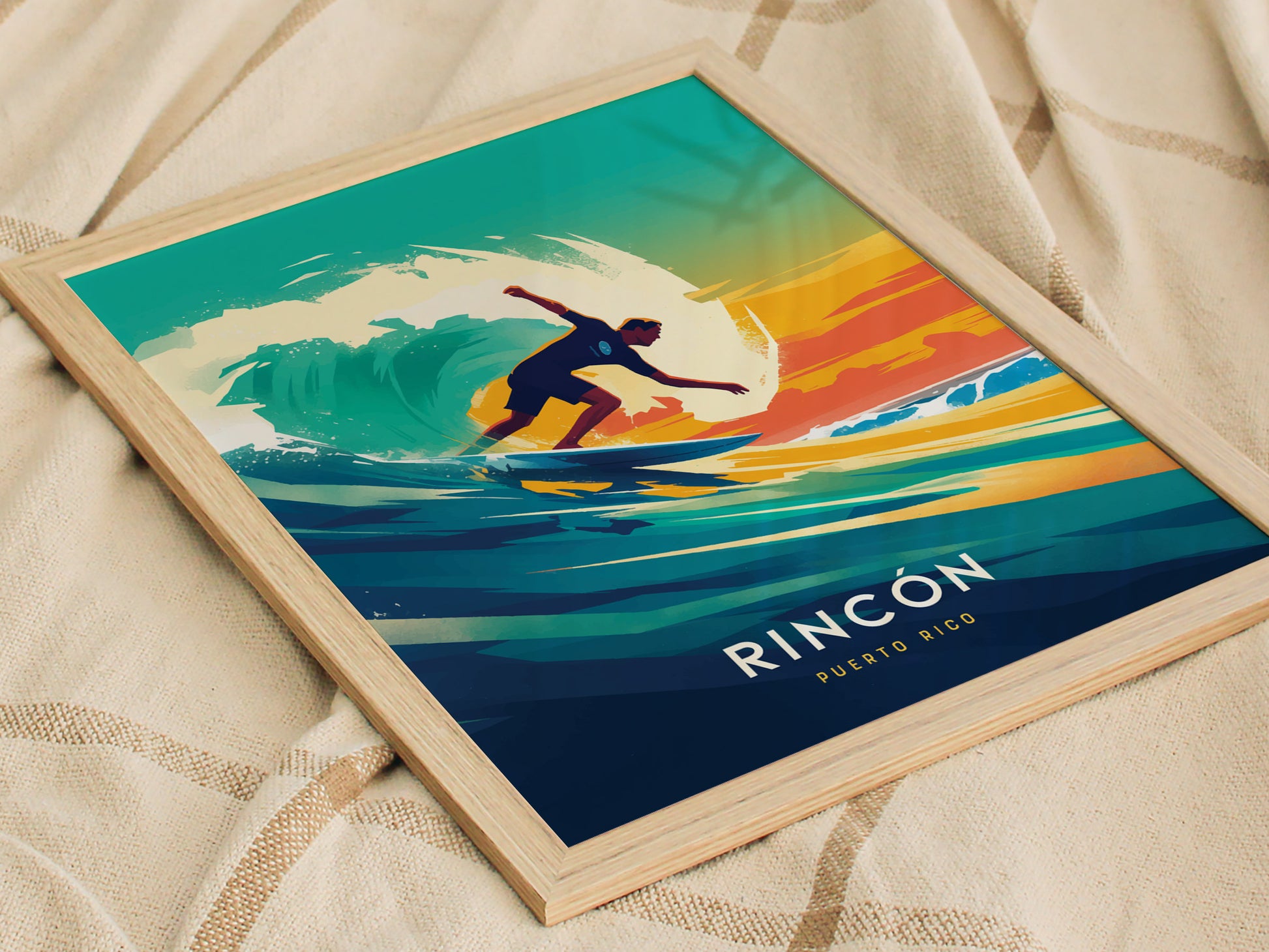 A framed poster featuring a surfer riding a vibrant wave against a colorful sunset, with Rincon Puerto Rico text at the bottom, displayed on a textured fabric surface.