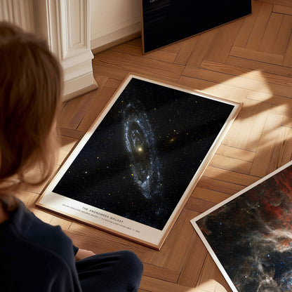 Person sitting on a wooden floor looking at space posters of galaxies