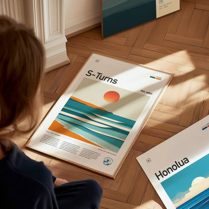 A person sits on a wooden floor, looking at a framed S-Turns poster depicting a stylized sunset over ocean waves, with another partial poster visible nearby.