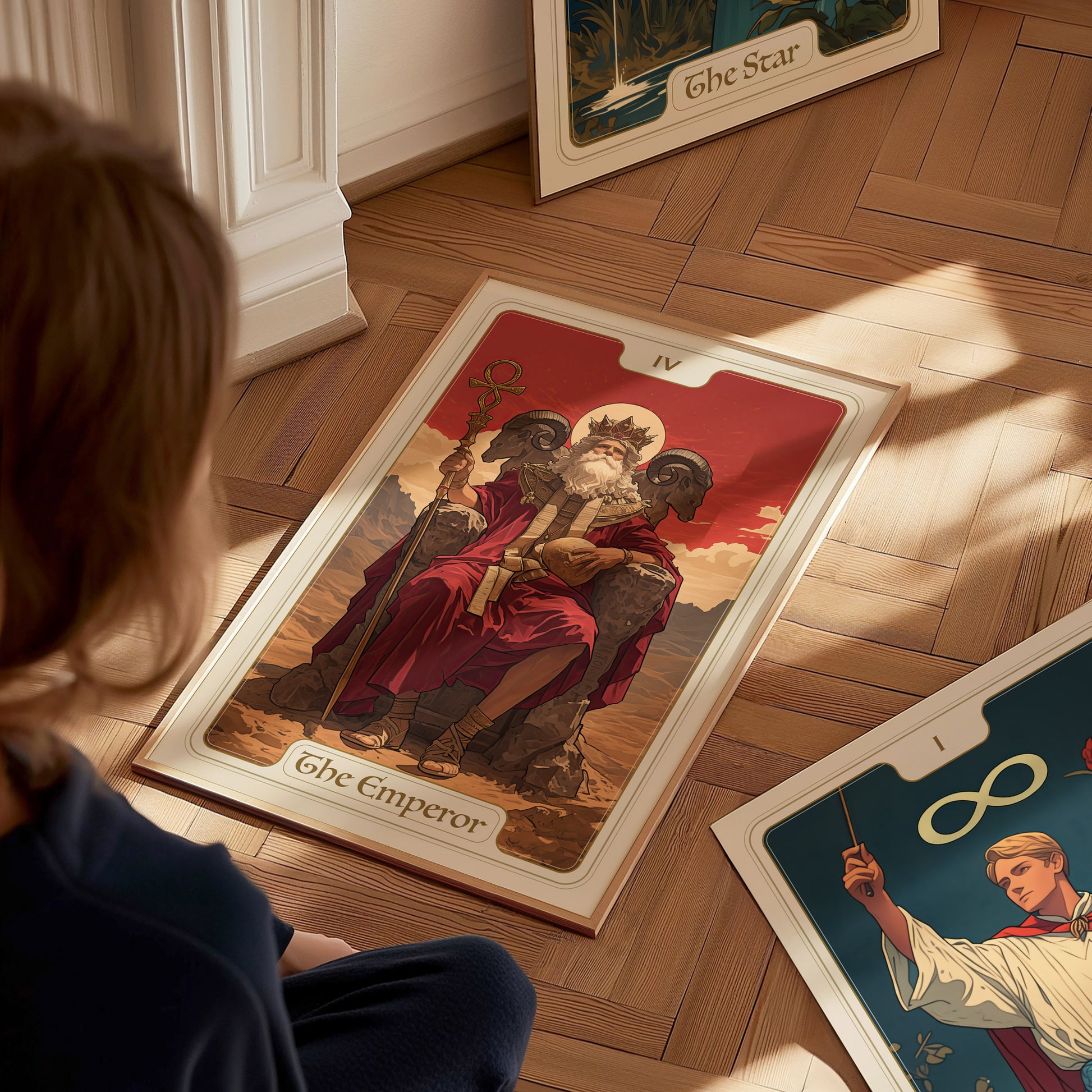 A person sits on the wooden floor, looking at a tarot card illustration of The Emperor, featuring a regal figure on a throne with mountains in the background.