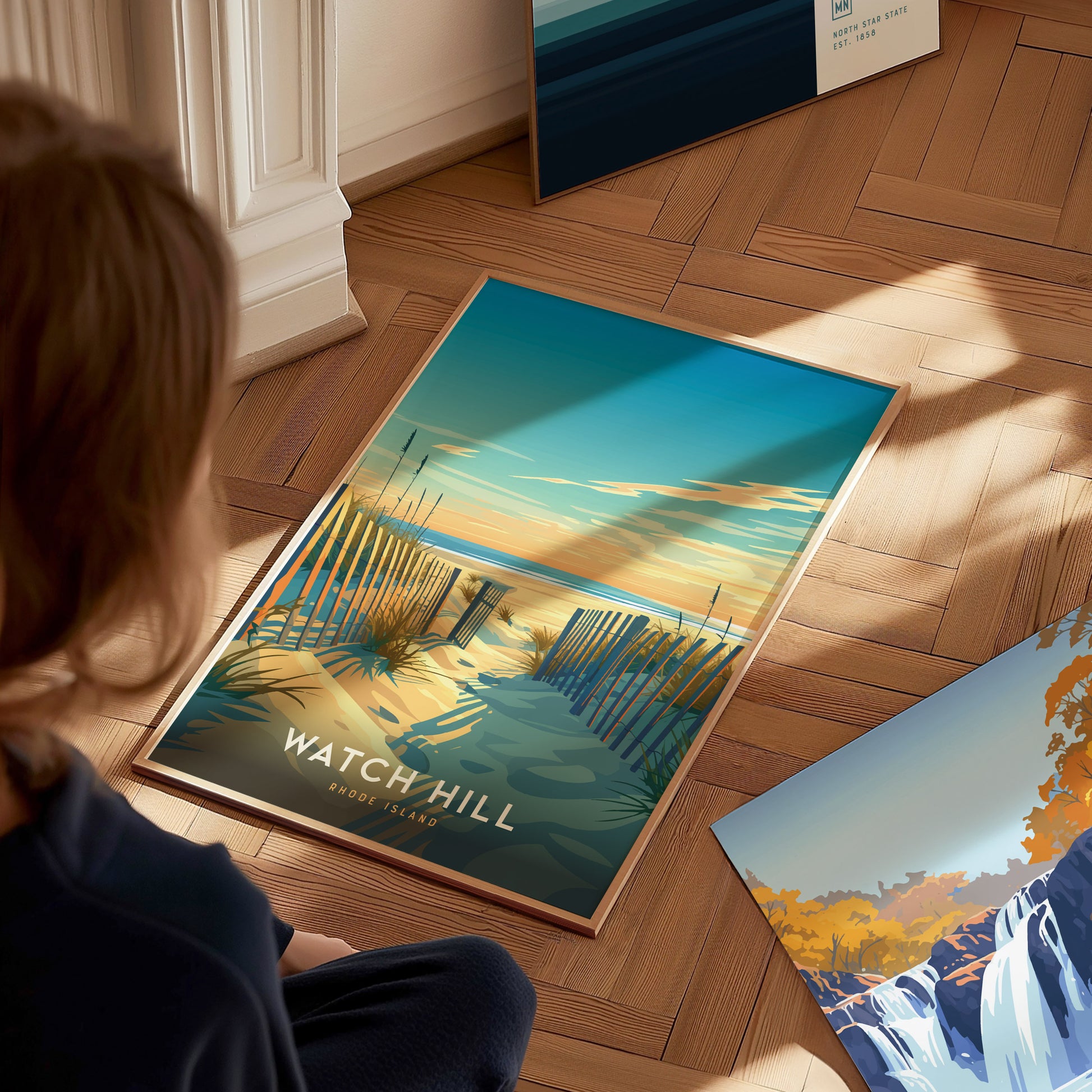 A person gazes at a vibrant Watch Hill, Rhode Island poster featuring a sandy beach path with wooden fences leading to the ocean under a colorful sky.