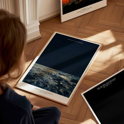 Person looking at framed space posters on a wooden floor