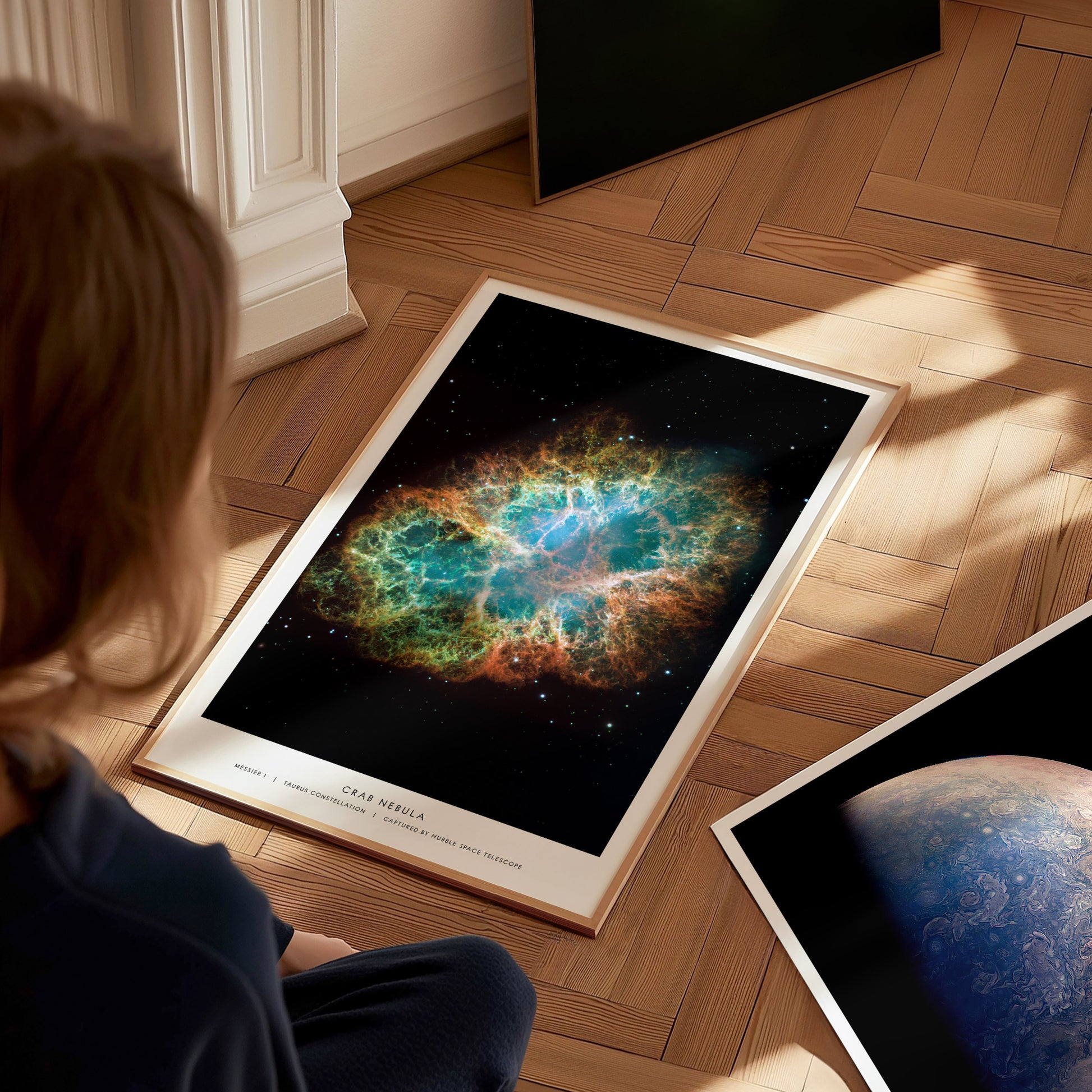 Crab Nebula artwork on the floor beside other astronomy prints, ready to be arranged as a cosmic-themed gallery wall.