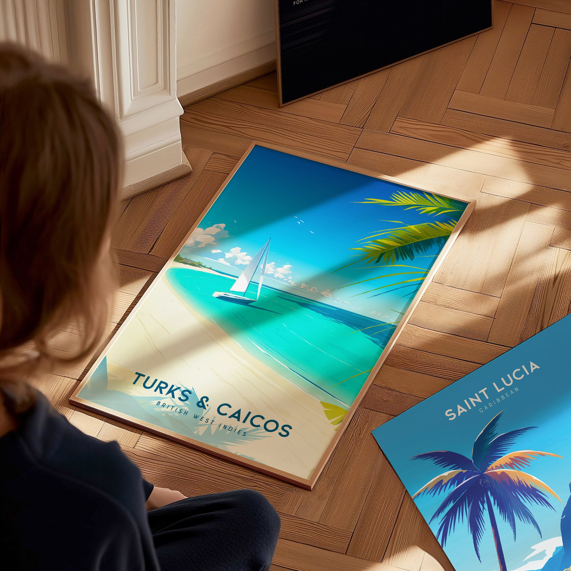 A child sits on a wooden floor, gazing at a colorful travel poster featuring a serene beach scene from Turks and Caicos, with a sailboat on turquoise waters and palm trees framing the image.