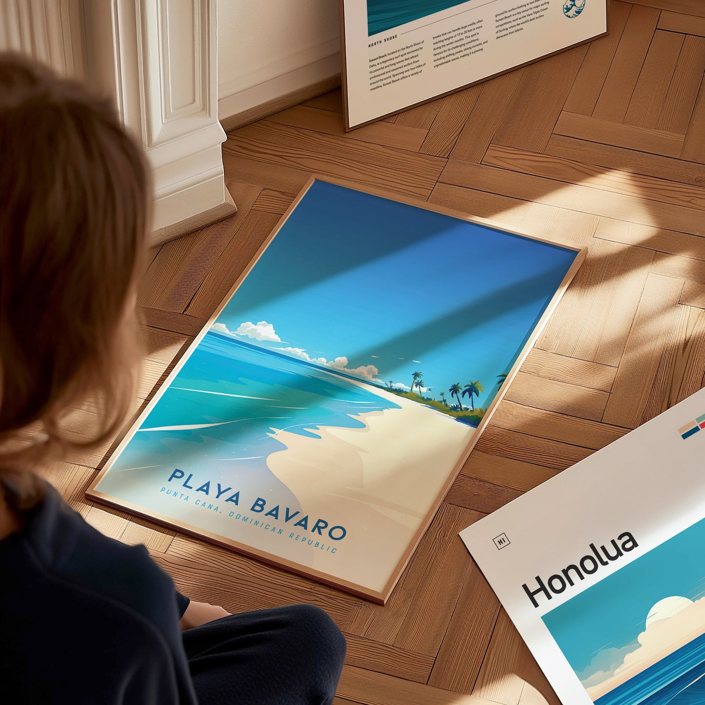 A person sits on a wooden floor, looking at a vibrant art print featuring a beach scene of Playa Bavaro in the Dominican Republic. The poster showcases a clear blue sky, soft white sand, and palm trees, evoking a tropical paradise feel.