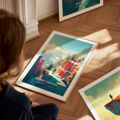 A person gazes at a framed Bryce Canyon National Park print on a wooden floor, featuring colorful canyon landscapes and hoodoo formations under a clear blue sky.