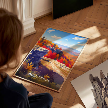 A child sits on a wooden floor, gazing at a vibrant poster of Dolly Sods, West Virginia. The artwork features colorful autumn foliage, rocky cliffs, and a clear blue sky, capturing the beauty of the natural landscape.