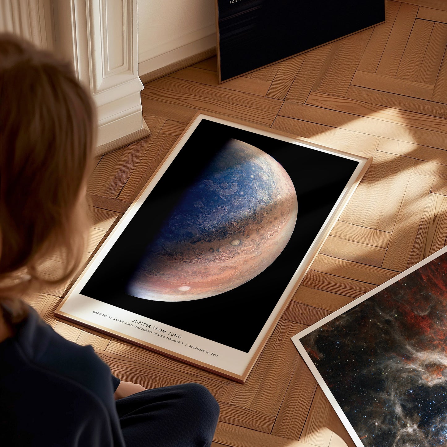 Person looking at a framed poster of Jupiter on a wooden floor