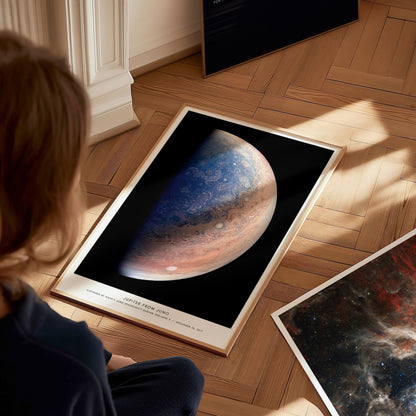 Person looking at a framed poster of Jupiter on a wooden floor