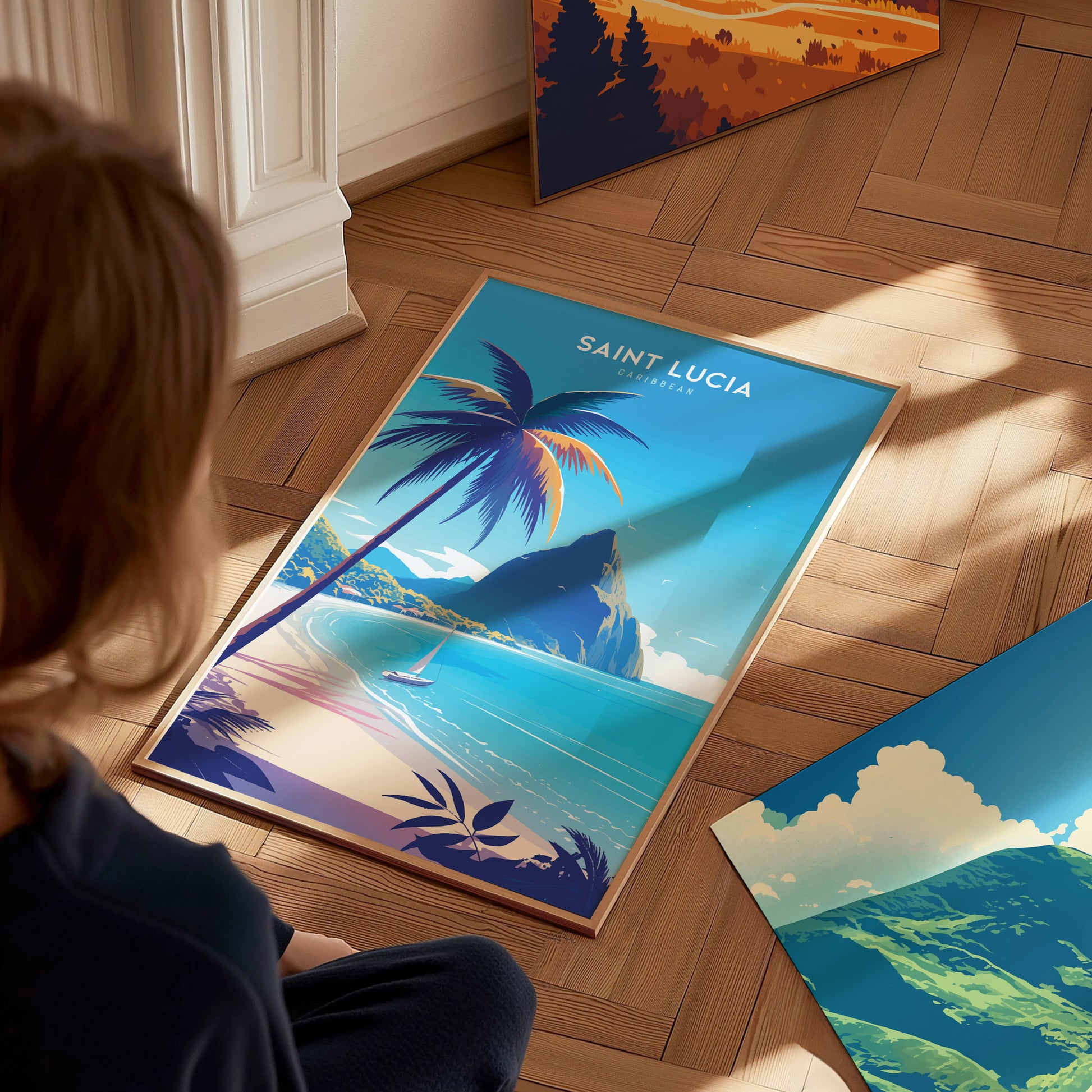 A person looks at a Saint Lucia poster featuring a tropical beach, turquoise waters, and the Pitons under a palm tree on a wooden floor. Additional vibrant artwork is nearby.