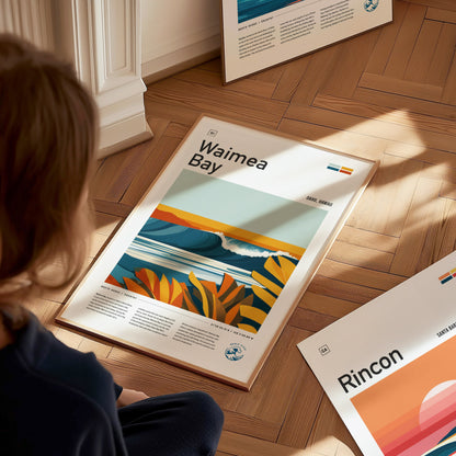 A person sits on a wooden floor, looking at a colorful Waimea Bay poster featuring waves and tropical foliage. Other posters are partially visible around them.