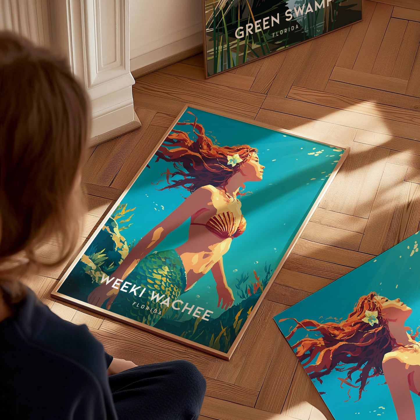 A child sits on a wooden floor, gazing at a vibrant poster featuring a mermaid with flowing hair and a seashell top, surrounded by shimmering blue water.