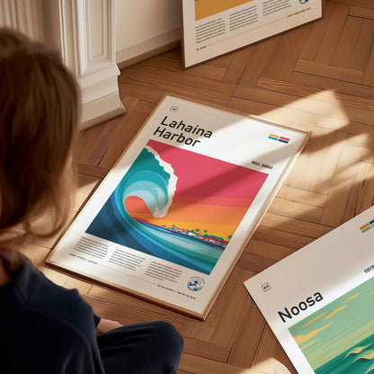 A person sits on a wooden floor, gazing at a colorful poster featuring a stylized wave and vibrant sunset over Lahaina Harbor in Maui, Hawaii. The poster showcases the essence of surf culture with bold colors and artistic design elements.
