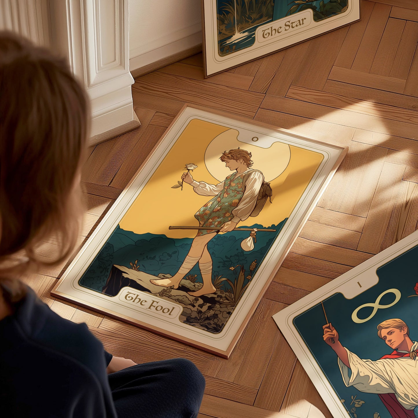 A person sits on the floor looking at a tarot poster of The Fool, depicting a wanderer with a white rose and a dog against a mountain backdrop.