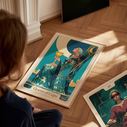 A child sits on a wooden floor, gazing at two tarot cards. One card, titled Queen of Cups, features a woman in a flowing blue gown holding a golden goblet, while the other card, partially visible, displays a young boy.