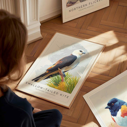 A child sits on a wooden floor, looking at a framed poster of a Swallow-tailed Kite perched on a green shrub. Other bird-themed posters are scattered nearby, highlighting various species in a cozy, well-lit room.