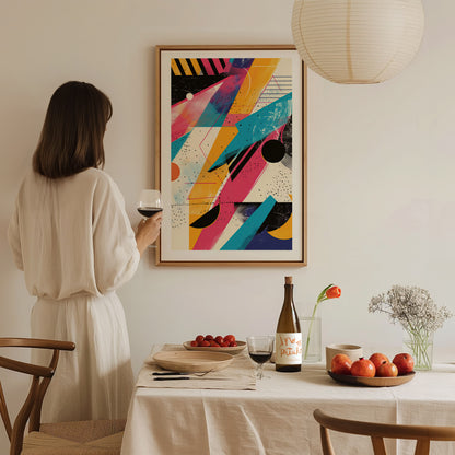 A woman in a beige dress holds a glass of wine, admiring a colorful abstract 80s-style poster on the wall, with a dining table set in front of her.