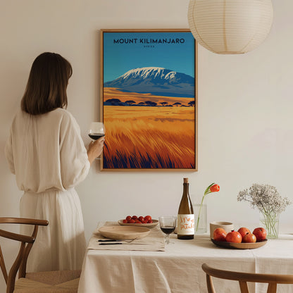 A woman in a white dress holds a wine glass, admiring a Mount Kilimanjaro poster on the wall. The dining table features fruits, wine,.