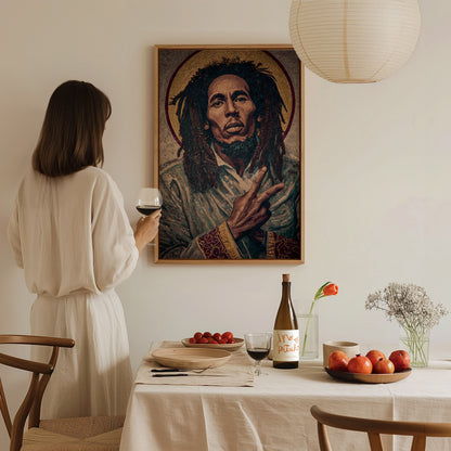 A woman in a light-colored dress stands at a dining table, holding a glass of wine and gazing at a large portrait of a man with dreadlocks on the wall.
