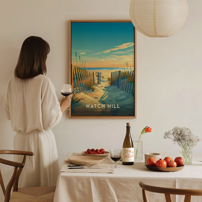 A woman in a white dress admires a framed Watch Hill Rhode Island poster, holding a glass of wine. The table is set with fruits, wine, and a vase of.