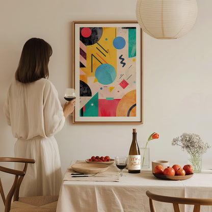 A woman holding a wine glass observes a colorful geometric abstract art poster on a wall. A dining table with fruit, wine, and flowers is in the foreground.
