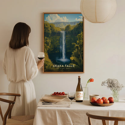 A woman in a light dress admires a framed Akaka Falls poster on the wall, holding a glass of wine. A dining table is set with fruits and flowers.