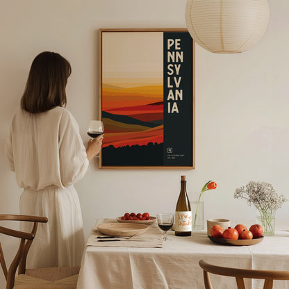 A woman in a white dress holding a glass of wine stands in front of a Pennsylvania poster with abstract landscape art.
