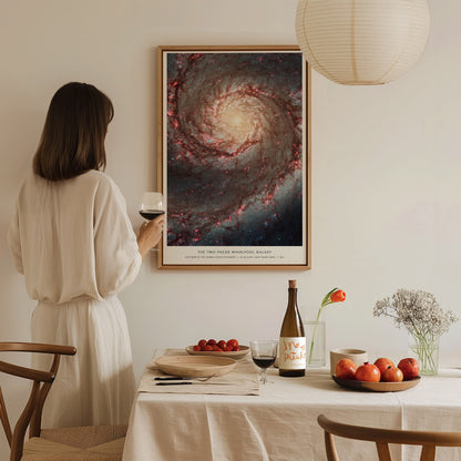 Woman in a white dress standing in a dining room with a large framed poster of a galaxy on the wall.