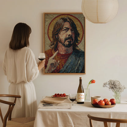 A woman in a white dress stands at a dining table, holding a glass of wine, gazing at a framed mosaic artwork of a man with long hair and a halo.