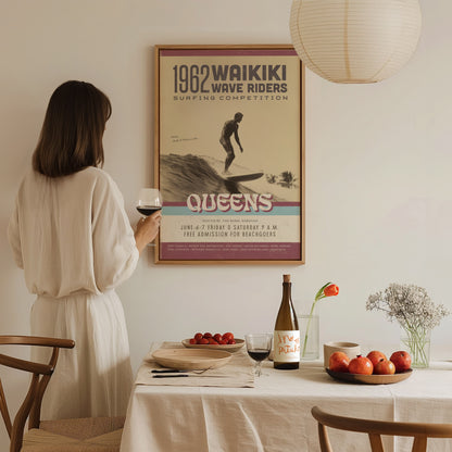A woman in a white dress holds a glass of wine, looking at a vintage 1962 Waikiki Wave Riders surf poster on the wall above a dining table.