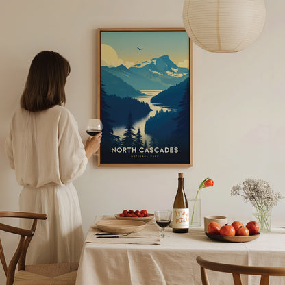 A woman in a white dress admires a North Cascades National Park poster, with a table set with wine, fruit, and flowers in the foreground.